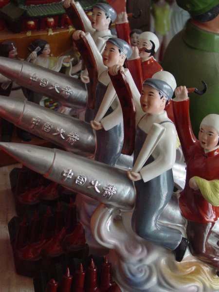 Figures on workers riding a missile at the Mao workshop