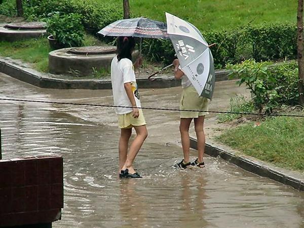 Two girls stamping their feet in a mud puddle