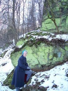 Nancy beside  large green lichen covered rocks.