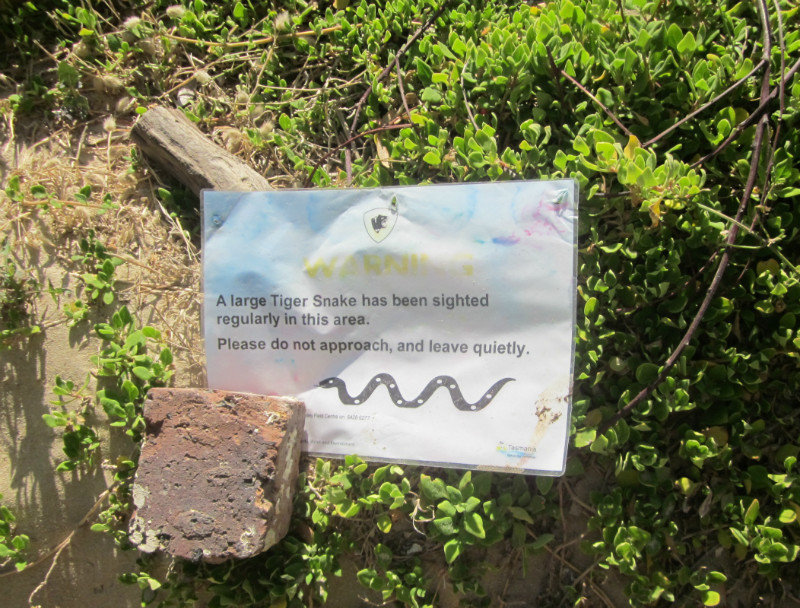 A sign on a path to the beach