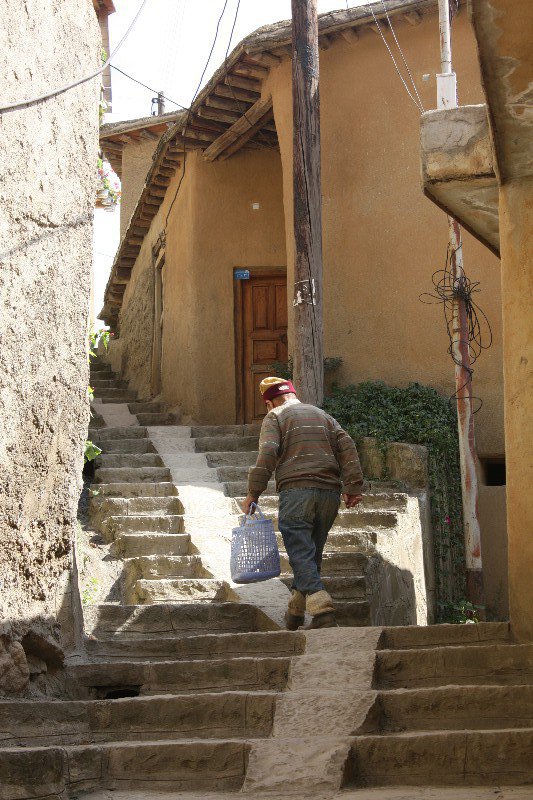 An elderly villager climbs higher into the village