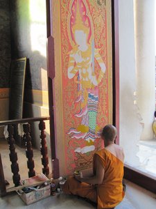 Thai Wat - Thailaendischer Moench beim Verzieren des Tempeltore