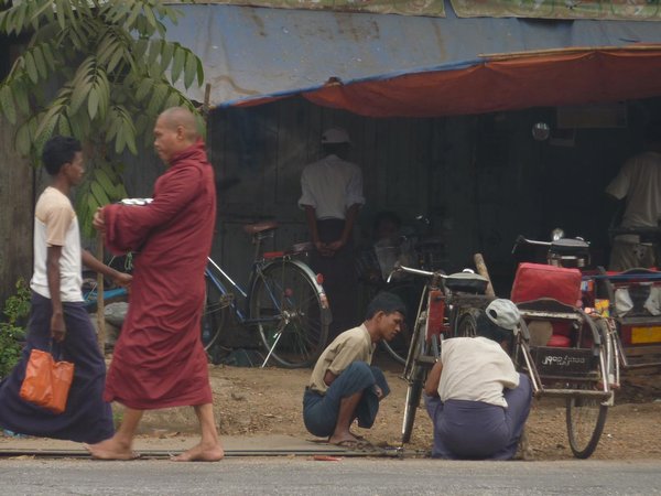 Monk passing by a bicycle repair shop