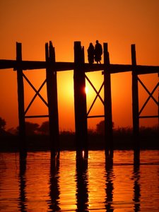 Monks crossing U Bein's bridge at sunset