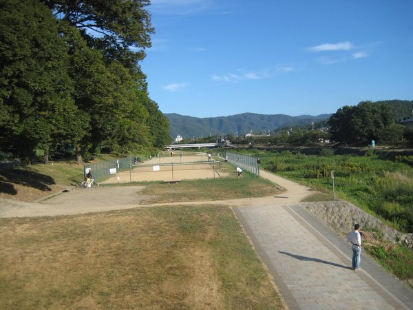 Playing tennis on sand court by Kyoto river