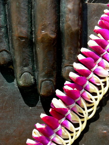 A lei draped over the hand of a statue