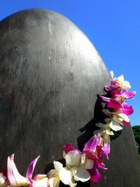 A lei draped over a surfboard statue