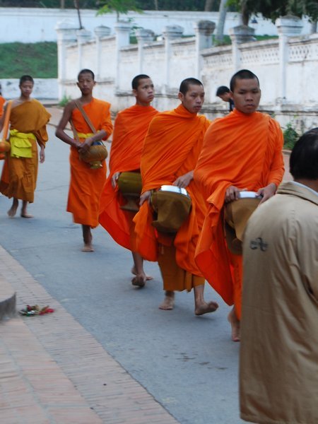 Collecting alms, note the monks at the head in all orange and the novices behind with yellow belt. 