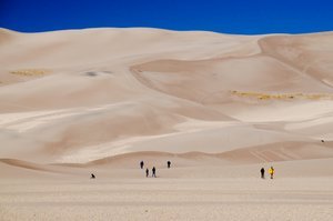 People walking at the base of the dunes