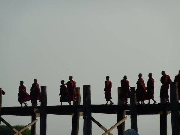 Monks crossing bridge as the day draws to a close