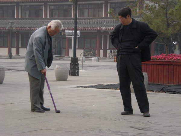 Old chinese guy painting on the floor