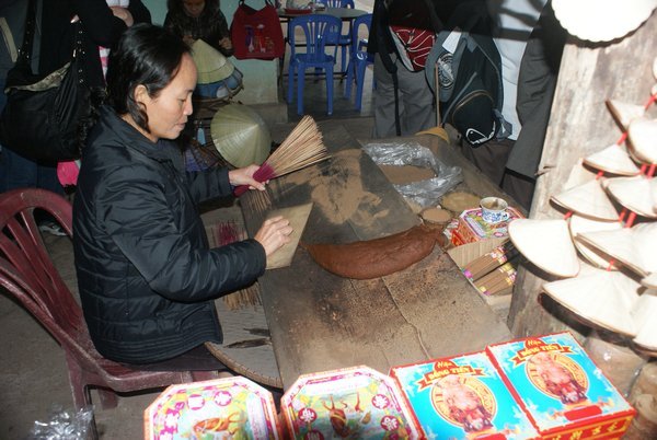 Lady making incense sticks. The big jobby looking thing is cinnamon paste that she rolls the sticks through.