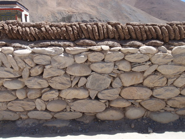 a typical wall decoratively topped with cow dung patties 
