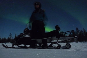 Snowmobiling at midnight under the Northern Lights
