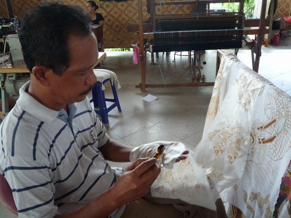 Batik artist applies liquid wax to the design