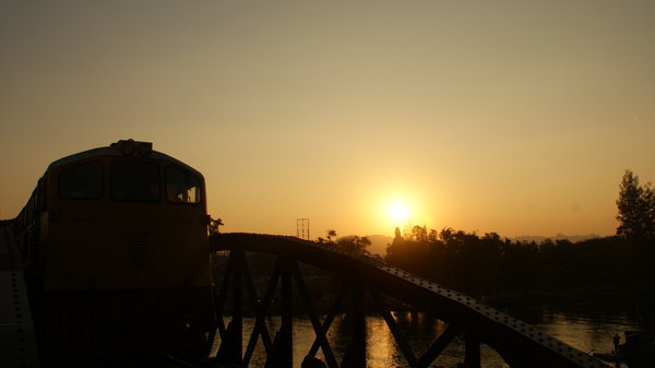 The train passing over the bridge in the dimming sun light.