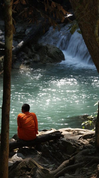 A Monk sits & enjoys the beauty of Erawan Waterfall.