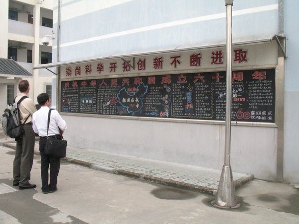 Jon and 'Dr. Hua examining a chalkboard on one of the school buildings