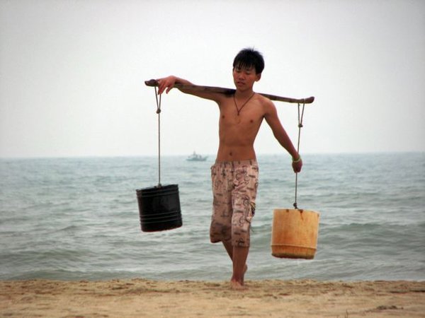 Boy carrying water from ocean to his home.