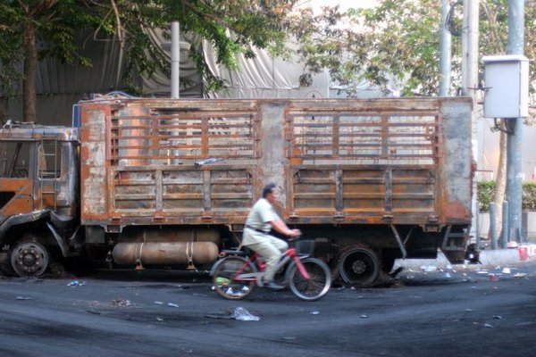 A local rides past a burnt out truck