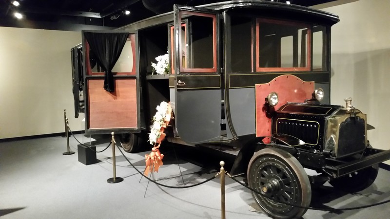 1916 Packard Funeral Bus With The Casket And The Flowers In The Middle Compartment And The Mourning Party in The Back