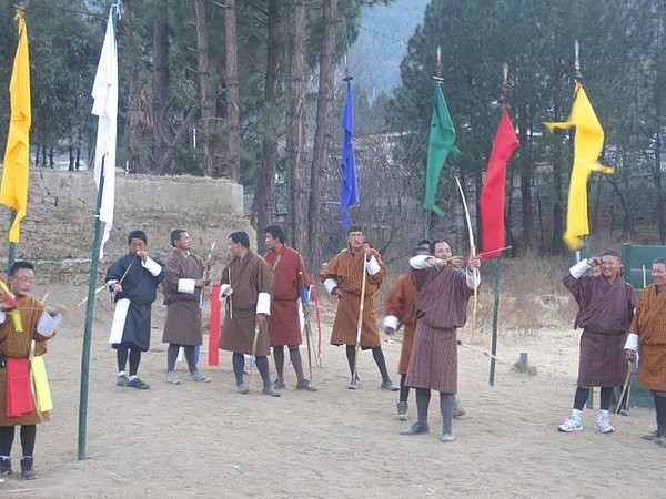 Men wearing traditional gho having a friendly archery contest