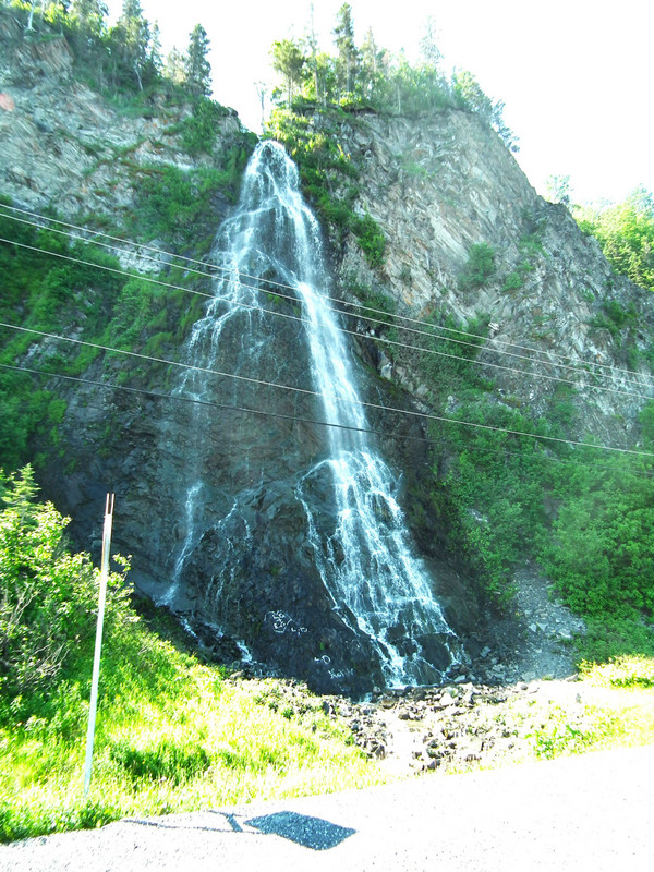 Tall waterfall on side of the road, alongside sea road