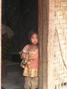 Shy village girl looking behind the door way