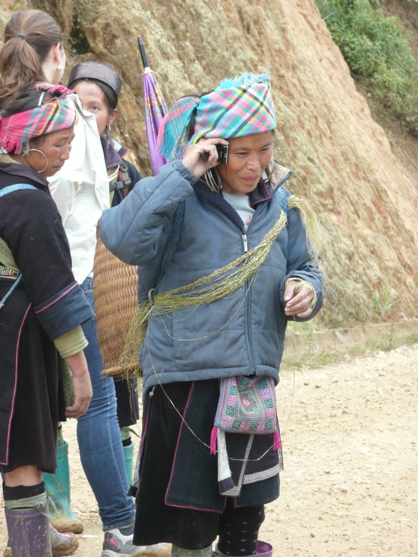 h'mong textile seller using mobile to contact her accountant