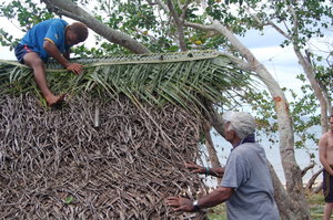 Namani, mending the thatch roof on Bebe's house.