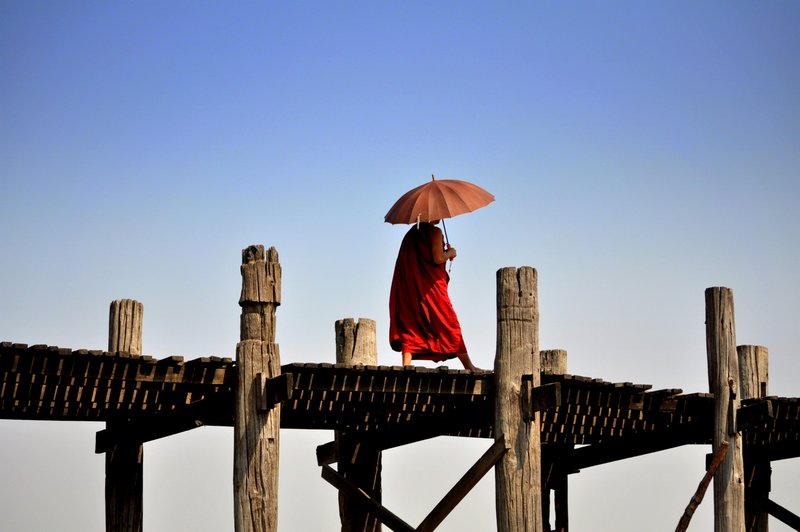 A monk crossing U Bein's Bridge