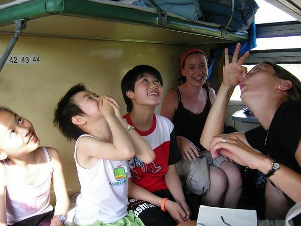 On the train, Julie, Flick and some Chinese children are unimpressed by the odour of my feet.