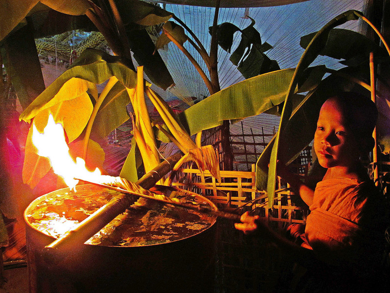 Novice and burning banana leaf, temple festival, Tad Lo.