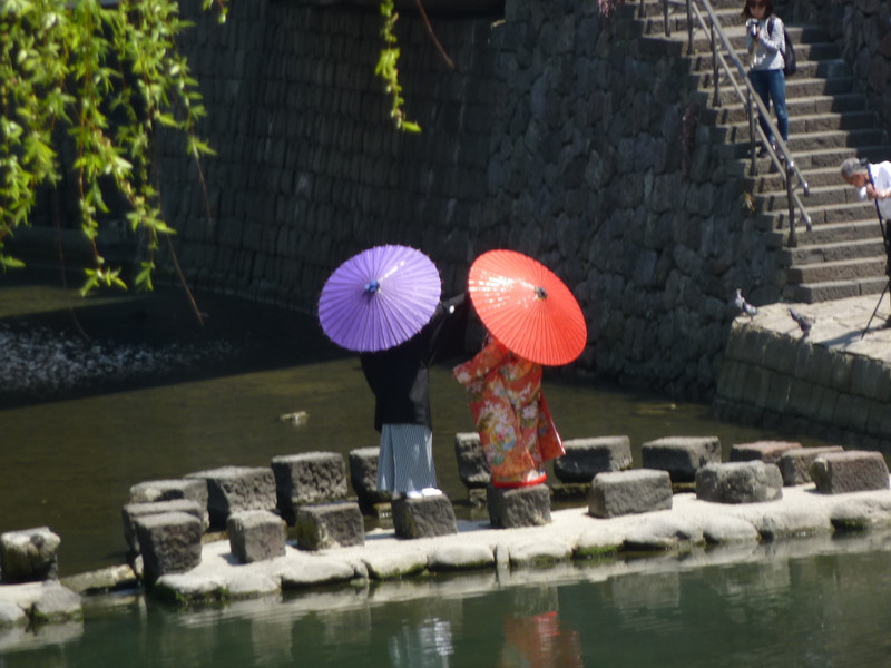 A new couple taking photos with the Meganebashi Bridge