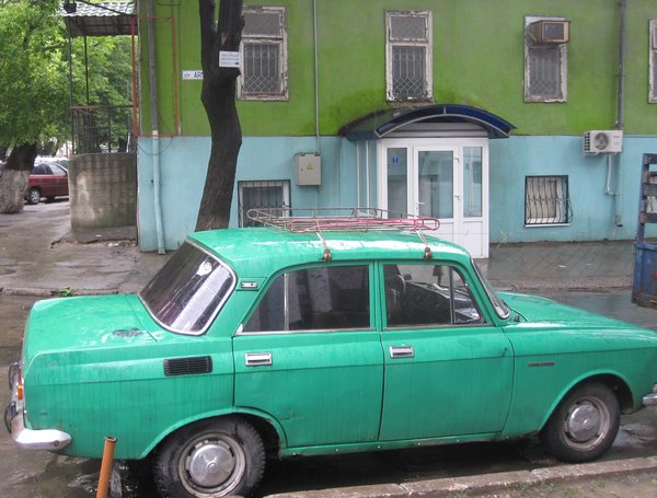 A green car in front a green building