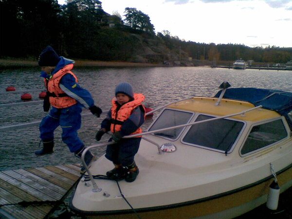 Isi pakkaa veneessä tavaroita, pojat harjoittelevat kansityöskentelyä 