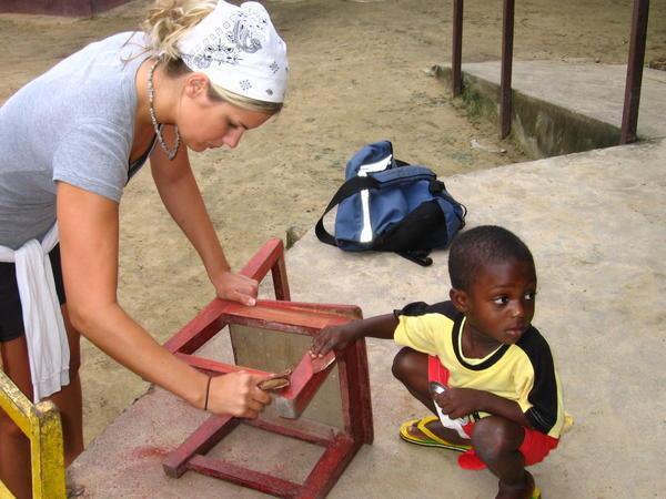 Kweku helping American student Elisha sand chair