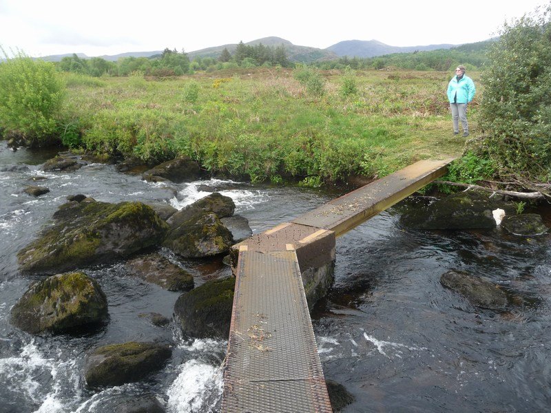 Helen contemplating bridge over stream, Glencar