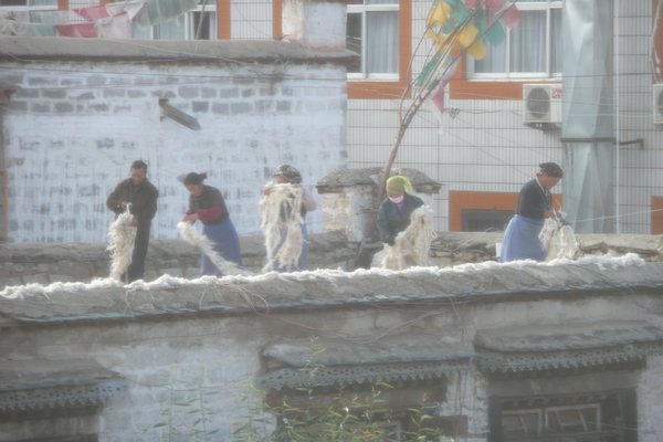 women pulling wool on a roof