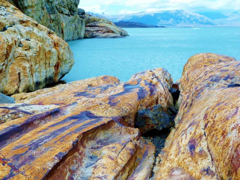 multi-colored rocks meet turquoise lake