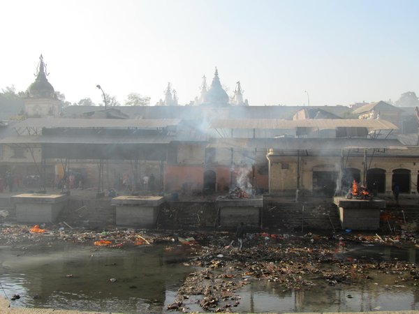 Hindutote werden vorm Fluss verbrannt und die Asche dann in den Fluss gestreut, man achte auf den Muell im Fluss