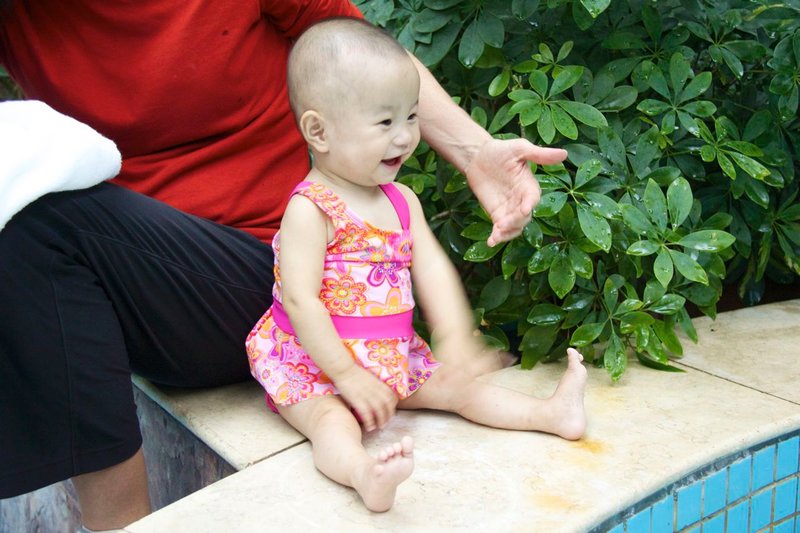 Pretty baby laughs at the antics of Emma & Josh in the toddler pool.