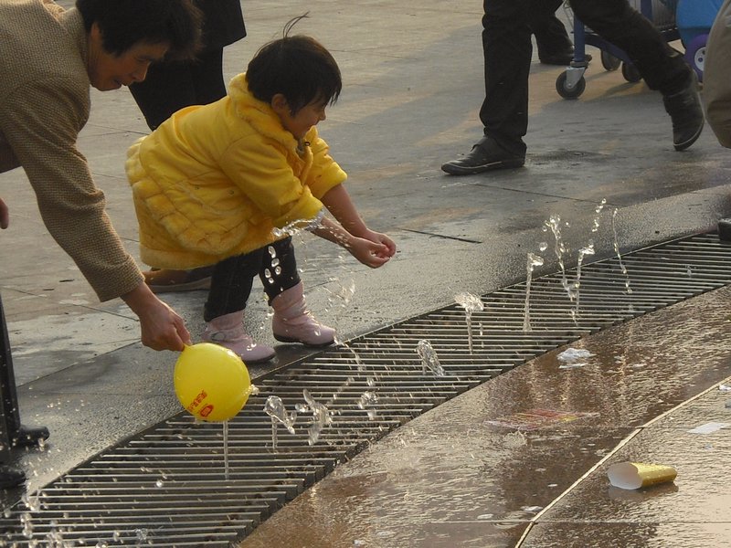 A Little Girl Plays in the Fountain