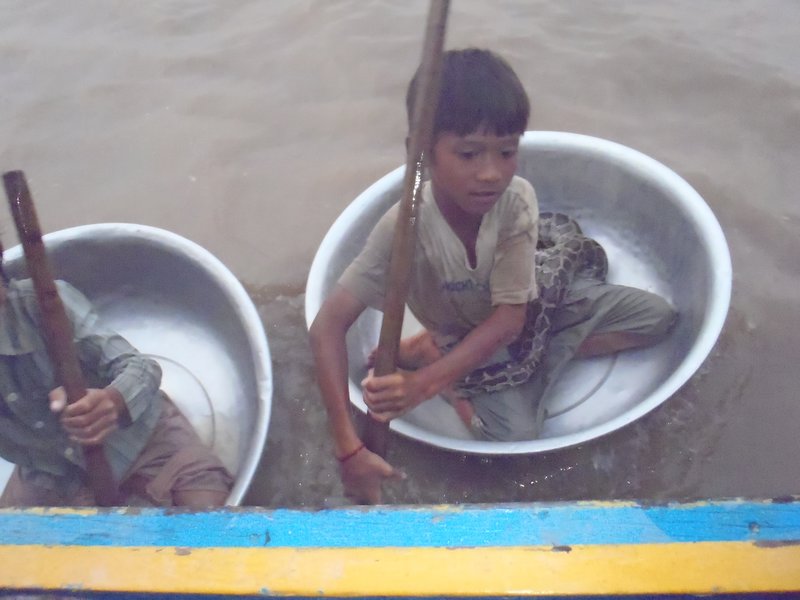 vietnamese child in his bucketboat!? and with a big phyton.