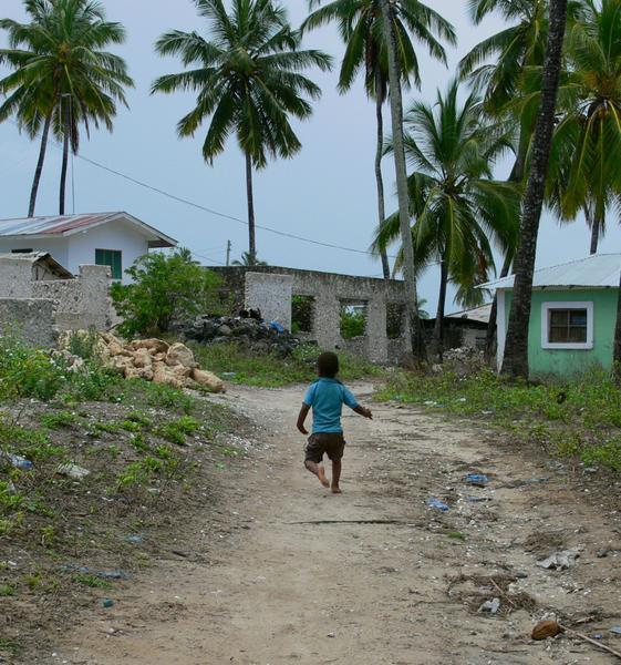 A child running in the village, none have shoes