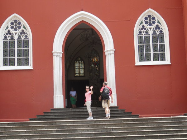 Front of red metal church in Grecias...me waving & Claude walking