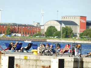 People sitting out on deck chairs near the harbour and cruise ship area