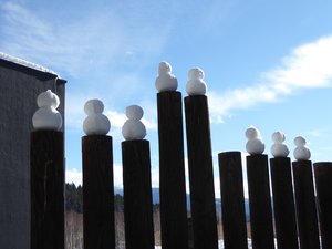 Someone built snowmen on top of fence