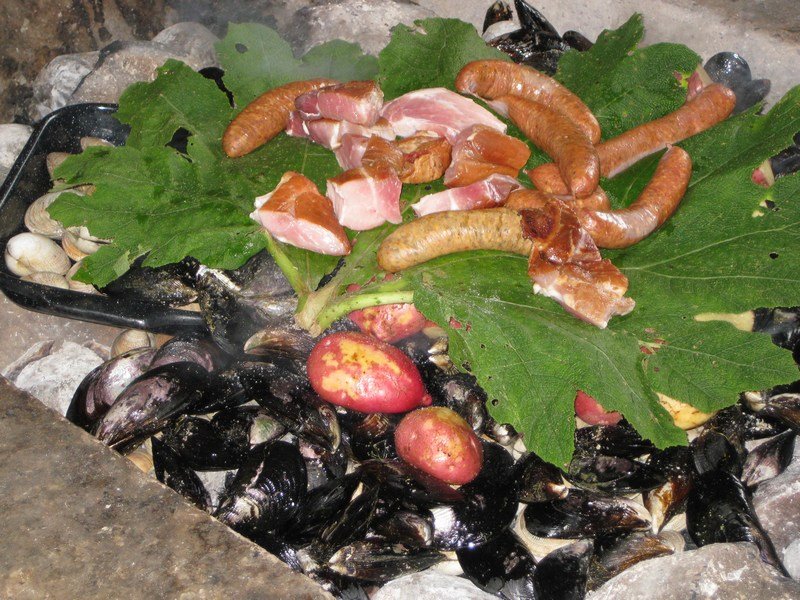 Curanto al hoyo - nalca leaves and the meat are added
