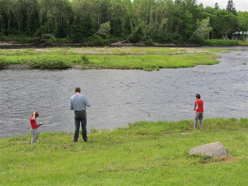Two boys fishing with dad helping